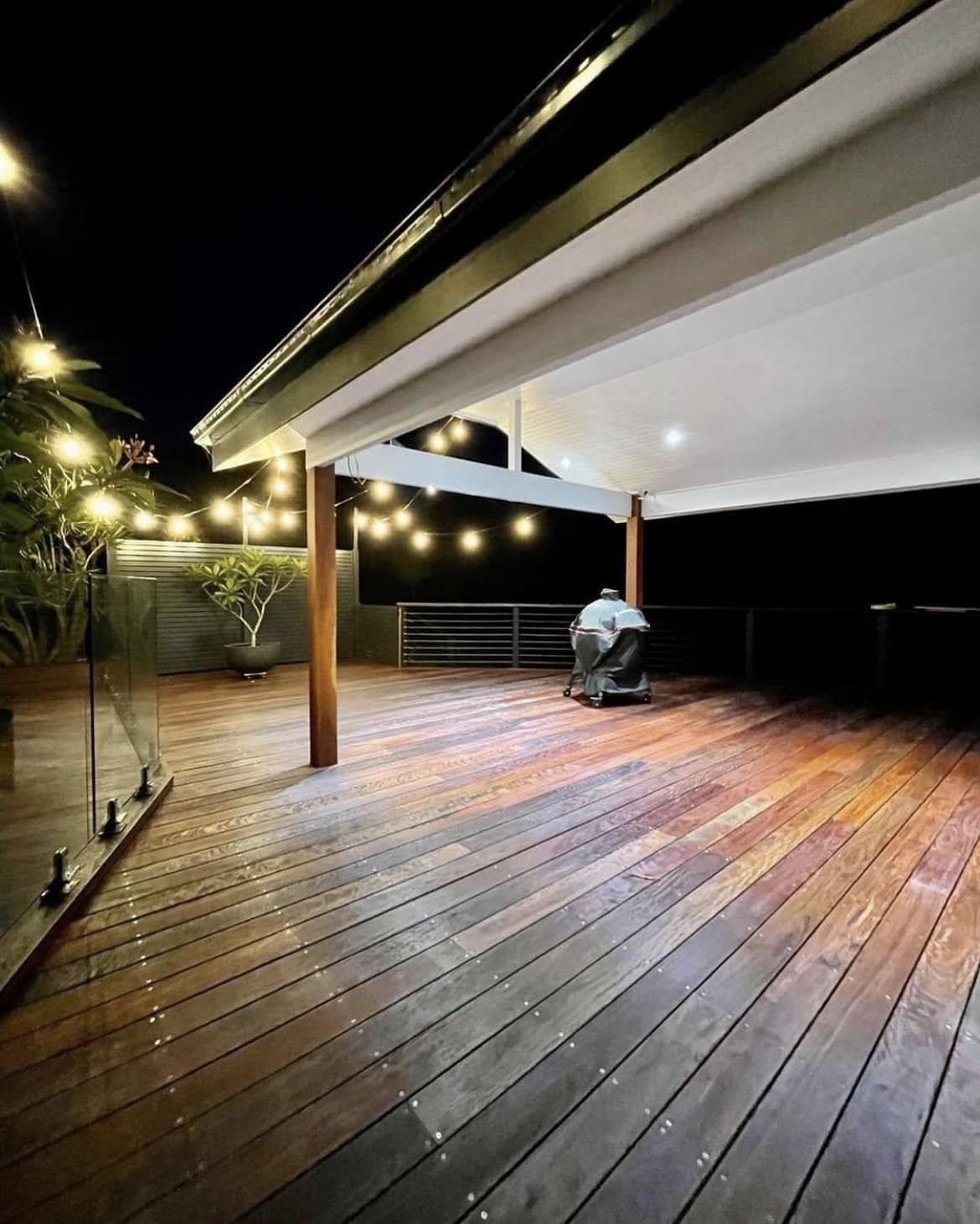 Hardwood deck lit by festoon lights at night, built by FLYNNBUILD